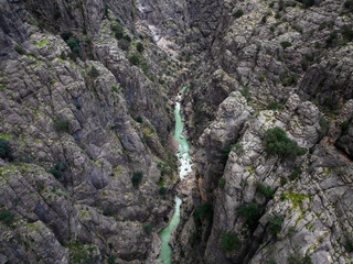 Overhead shot showcasing the winding river through Tazı Canyon with lush vegetation on rugged cliffs, captured in Antalya.