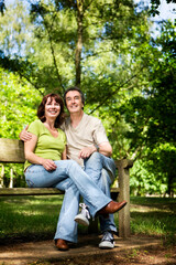 Life begins at 40. A candid and affectionate moment between a  mature couple enjoying time together in a sunny woodland park.