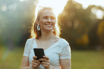 smiling 40 years old woman in shirt using smartphone app