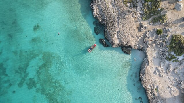 Aruba Tres Trapi snorkeling vertical areal photo of clear turquoise water with boat and rocky coastline
