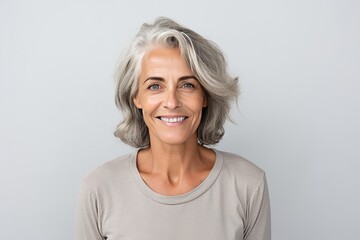 Portrait of smiling senior woman with grey hair isolated on grey background