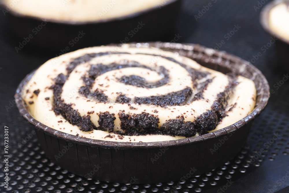 Poster a small dessert with a swirl of chocolate and cinnamon on top. the dessert is in a small pan and is 