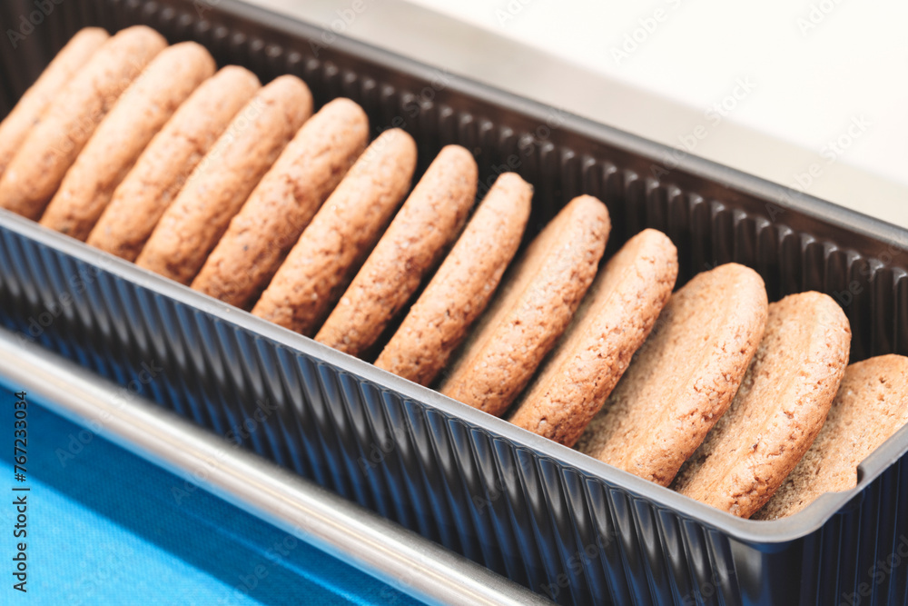 Poster A tray of cookies is sitting on a counter. The cookies are all the same size and are arranged in a row
