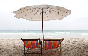 Beach chairs and white parasol on the white sand beach