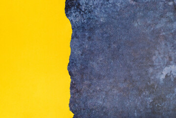 Piece of yellow torn paper on blue surface. Space for text.