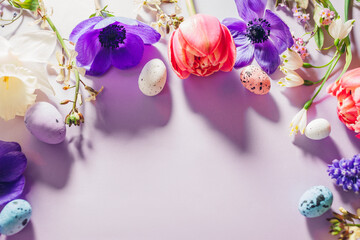 Happy Easter mockup. Easter eggs with spring pink purple flowers flat lay on purple background. Greeting card banner