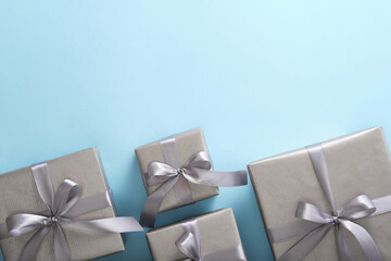 Monochrome gray gift boxes with silver ribbons on light blue background. Copyspace