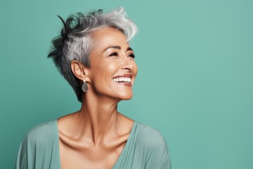 Beautiful smiling middle aged woman with grey hair on turquoise background