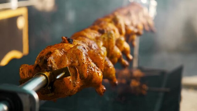 Close up video of grilling whole chicken outdoors.