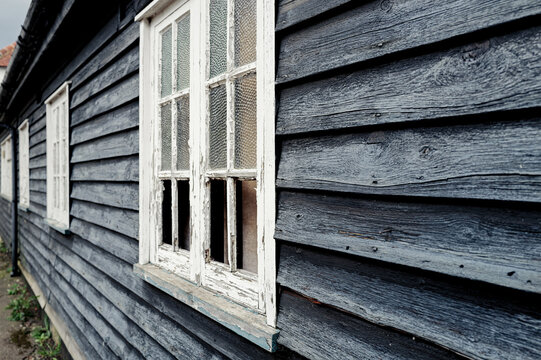 Old English wooden former Inn now derelict in a village location. The rough wooden panels and flacking windows are evident, prior to restoration.