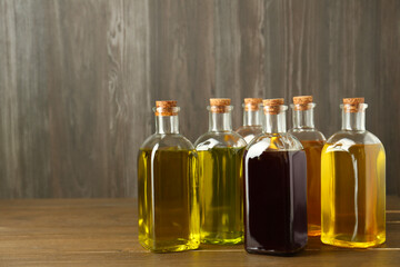 Vegetable fats. Different oils in glass bottles on wooden table, space for text