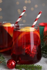 Delicious Sangria drink in glasses and Christmas decorations on grey table, closeup