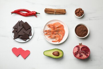 Natural aphrodisiac. Different products and paper hearts on white marble table, flat lay