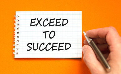 Exceed to succeed symbol. Concept words Exceed to succeed on beautiful white note. Beautiful orange background. Businessman hand. Business and exceed to succeed concept. Copy space.