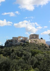 Fototapeta na wymiar Summer Splendor: Acropolis Beneath Blue Skies and Fluffy Clouds