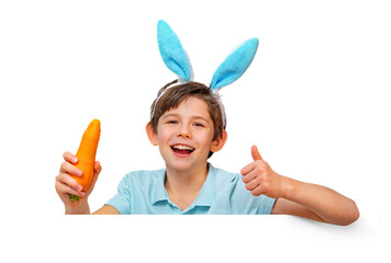 Funny child in hare ears with a carrot in her hand. The boy loves healthy food, holds a carrot in...