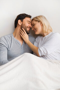 Portrait image - young attractive couple at each other, profile side on bed. Blond woman with brunette bearded man in love, relationship, dating, happy family, waiting child concept.