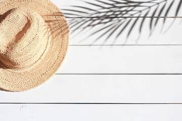 Summertime, vacation, travel, tourism concept. Summer straw hat and shadow of palm leaves on white...