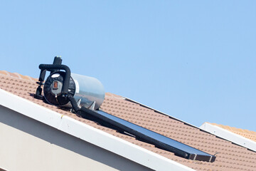 Rooftop solar hot water geyser on the roof of a house with photovoltaic panel, renewable energy,...