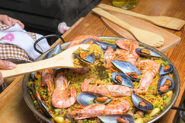 Seafood paella with prawns in a pan beside wooden utensils, typical Spanish cuisine, Majorca, Balearic Islands, Spain