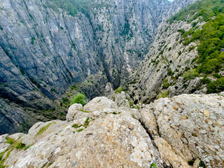 Aerial view of Tazı Canyon in Antalya showing steep cliffs and greenery, capturing the scale and rugged terrain of the natural gorge from a high vantage point.