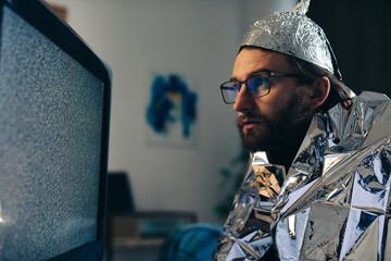 Man in Tin Foil Hat and Blanket Watching TV Interference - obrazy, fototapety, plakaty