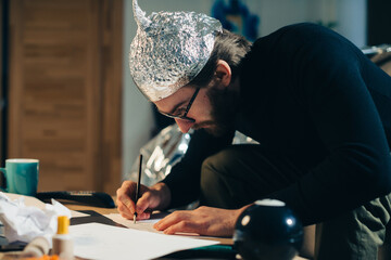Unveiling Conspiracies: Man in Foil Hat Crafting Cryptic Signs