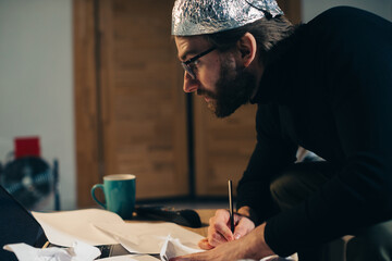 Symbolic Secrets: Man in Tin Foil Headgear Sketching Esoteric Signs