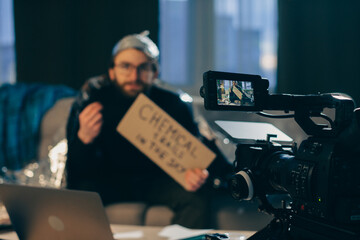 A conspiracy theorist shoots pseudoscientific videos on camera. A man in a tinfoil hat and a sign...