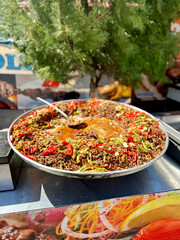 Traditional Turkish tantuni dish served in a large pan, topped with fresh green and red peppers, capturing the essence of street food culture in Turkey.