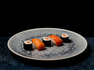 sushi preparado sobre hojas plato y pizarra con fondo negro