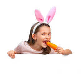 Funny little girl wearing bunny ears with a carrot in her hand. The child eats a carrot. Isolated...
