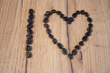 coffee beans in the shape of a heart on a wooden background.