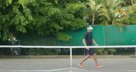 Man in augmented virtual reality headset plays tennis outdoor. - Powered by Adobe