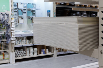 Stack of drywall sheets on a rack in a hardware store.
