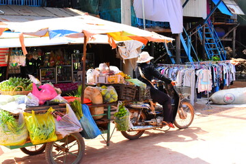 Naklejka premium SIEM REAP, CAMBODIA - April 22, 2023: Unidentified Khmer woman selling fish at food marketplace on April 22, 2023 in Siem Reap, Cambodia. Street food markets is popular tradition in asia