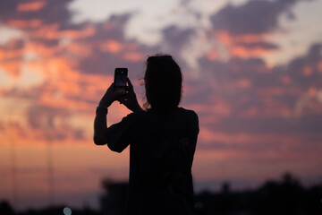 Silueta de hombre fotografiando el atardecer con su teléfono celular
