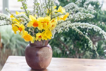Zelfklevend Fotobehang Still life with daffodil flowers in vase on table with blurred background. © Viliam