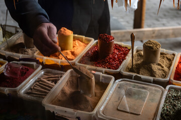 A man scoops freshly ground spices at an outdoor food market in Tbilisi, Georgia.
