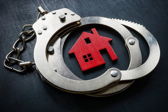 Model of home and handcuffs. Property fraud concept.