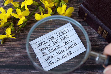 Seek the LORD while He may be found, handwritten quote with magnifying glass and holy bible book....