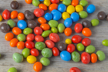 Peanuts in chocolate multi-colored glaze on a wooden table. Top view.