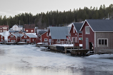 a bunch of red wooden buildings near a river and trees