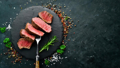 Grilled beef steak with herbs and spices on a black background, top view