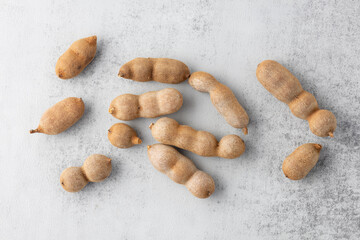 Ripe whole tamarind fruits on stone background.