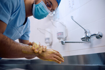 Male doctor washing hands while getting ready for  surgery at clinic.