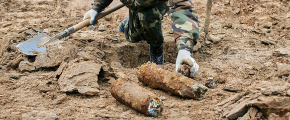 Military personnel extracting live mortar shell during demining operation