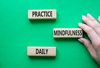 Practice Mindfulness Daily symbol. Concept words Practice Mindfulness Daily on wooden blocks. Businessman hand. Beautiful green background. Medical and Psychology concept. Copy space.
