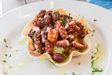 Tasty grilled octopus with potato and olive on a table in restaurant. Top view
