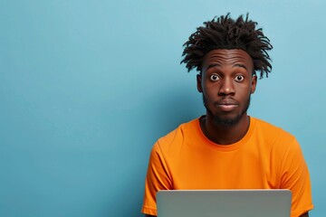 Portrait of a confused puzzled minded African American man in orange top with laptop isolated on blue background, with copy space. - obrazy, fototapety, plakaty